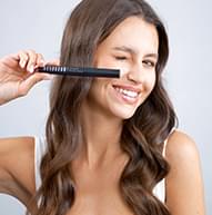 Fyrirsæta blikkar og brosir, heldur Shape Mascara nálægt andlitinu